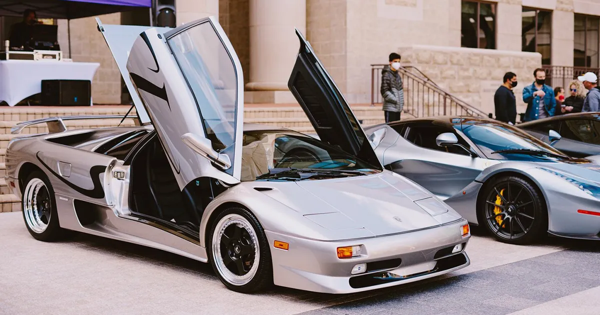 The all-action Diablo was a 90s hero. Silver supercar with open scissor doors sitting on a plaza.